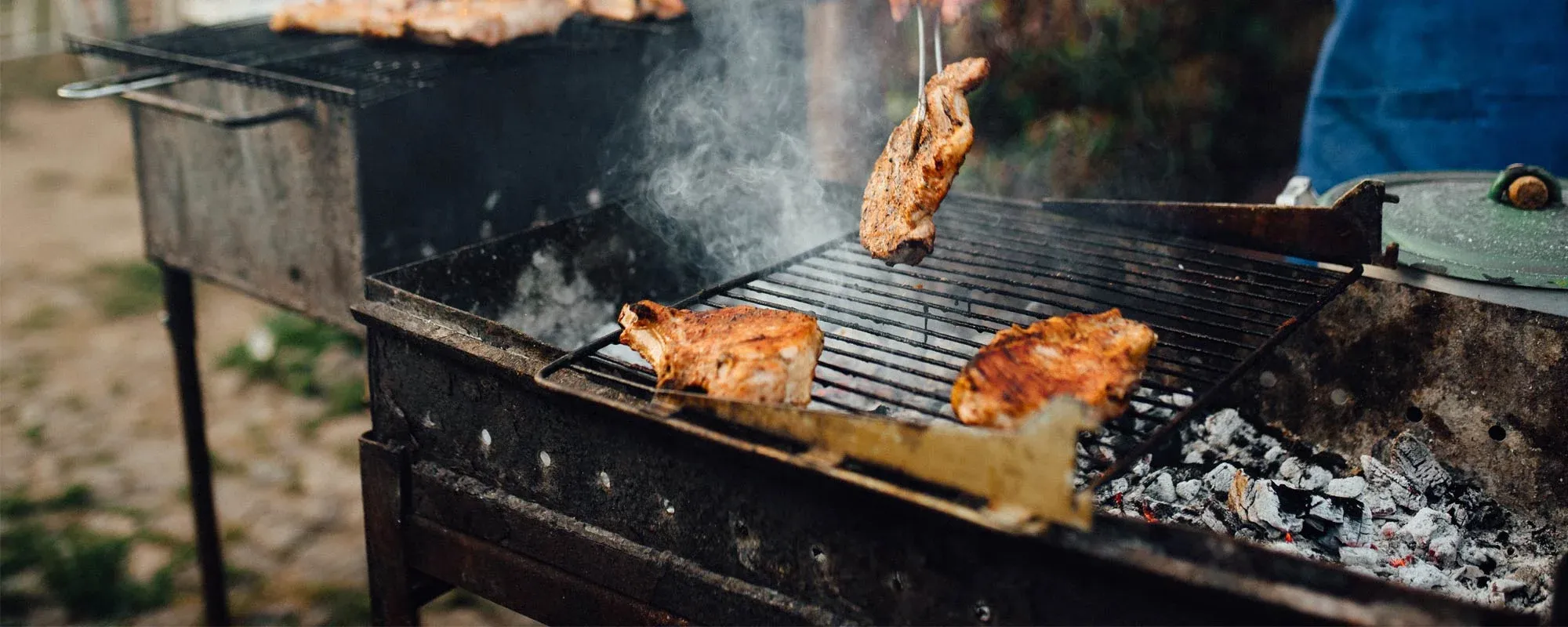 Burgers cooking over the flames on a Castlemeats charcoal grill